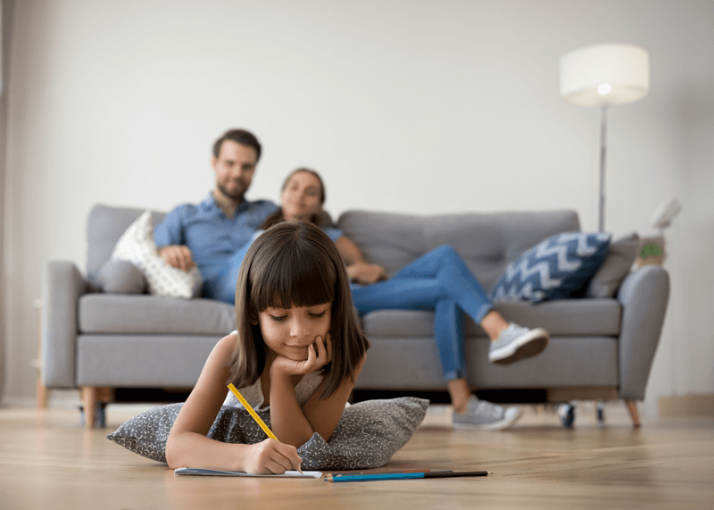 Parents on couch watching daughter draw